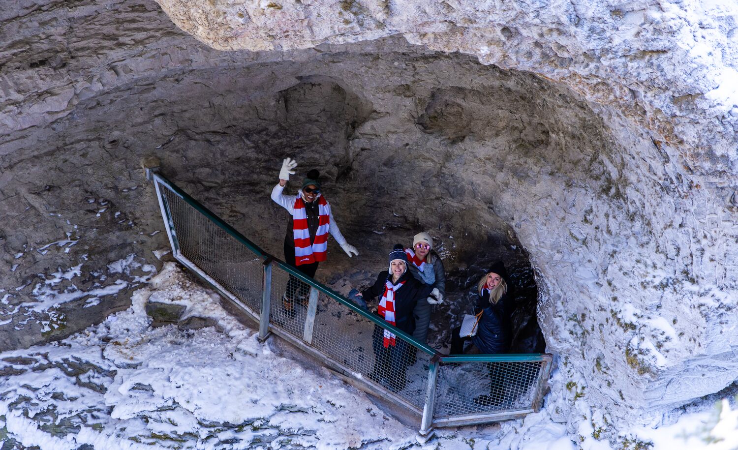 People wave from a cave on Johnston Canyon trail in winter in Banff National Park.